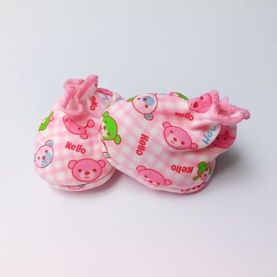 Pair of pink baby booties with cartoon designs on a light gray background